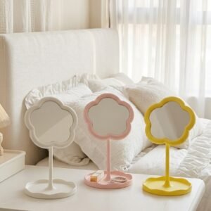 Floral makeup mirror on a bedroom dresser beside a small tray and a candle