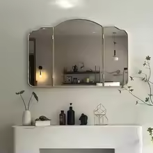 Triple fold wall mirror with retro stainless steel frame hanging above a hallway console table